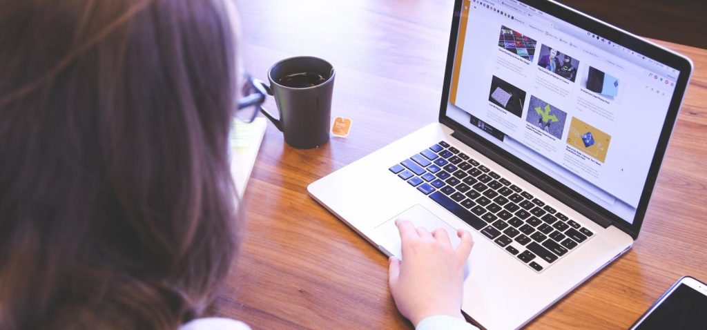 Kobieta siedząca przy biurku, korzystająca z laptopa